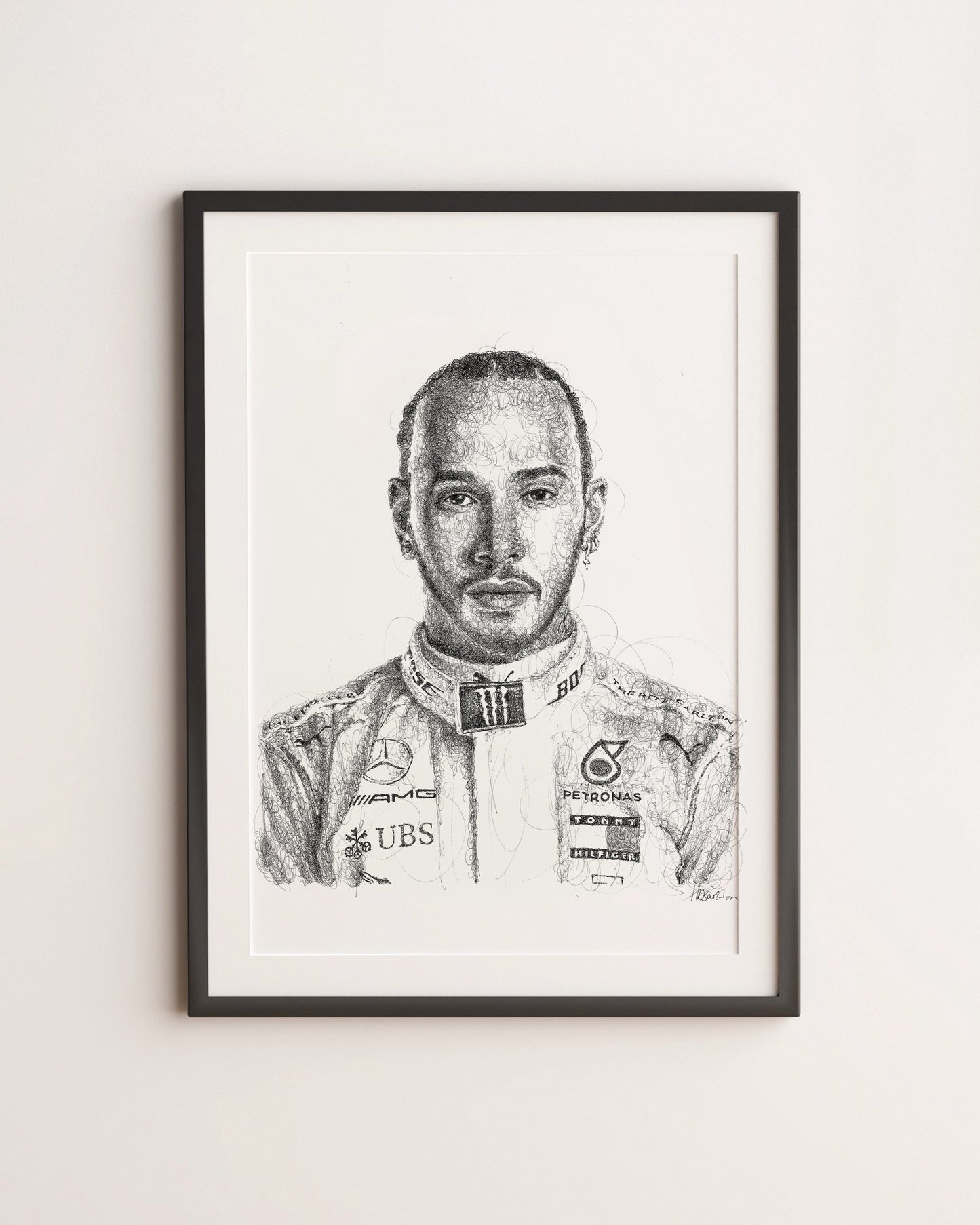 Framed black and white portrait of a Formula 1 driver Lewis Hamiltonn on a light gray wall
